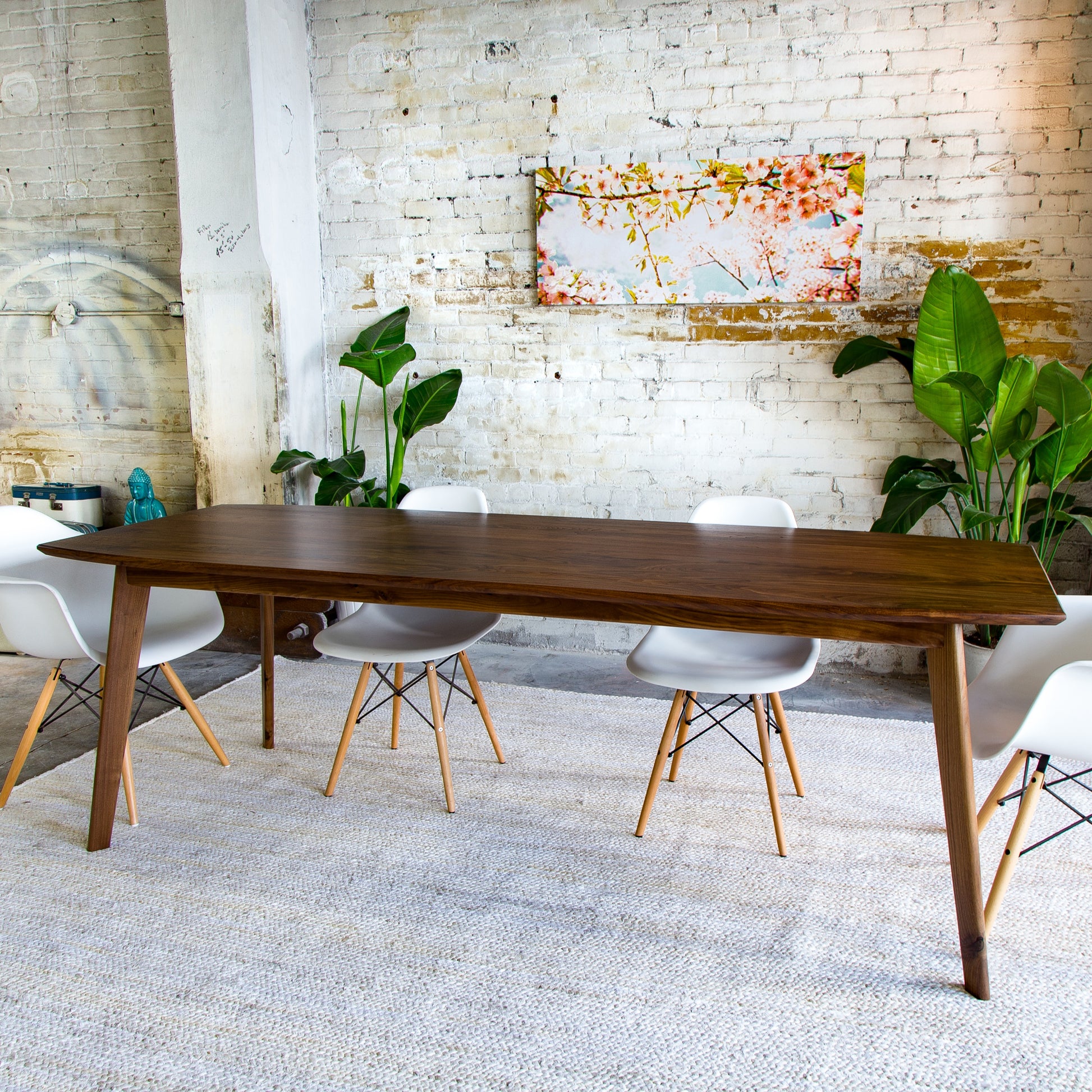 Discover sustainable luxury with the Santa Monica dining table, blending mid-century charm with modern craftsmanship. (Pictured: A handcrafted walnut dining table with a sleek semi-elliptical top and tapered legs.)