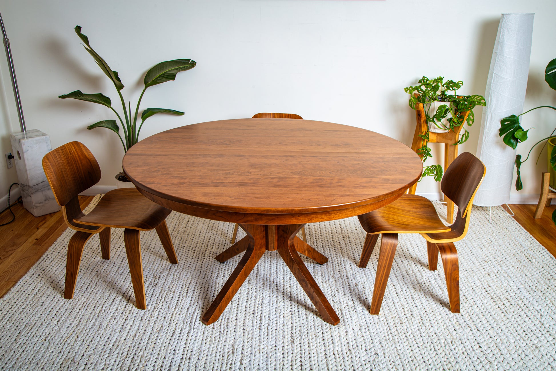 Corcovado: Modern Small Dining Table for 4 to 8, shown round with chairs, showcasing its extendable hardwood design for versatile dining needs.