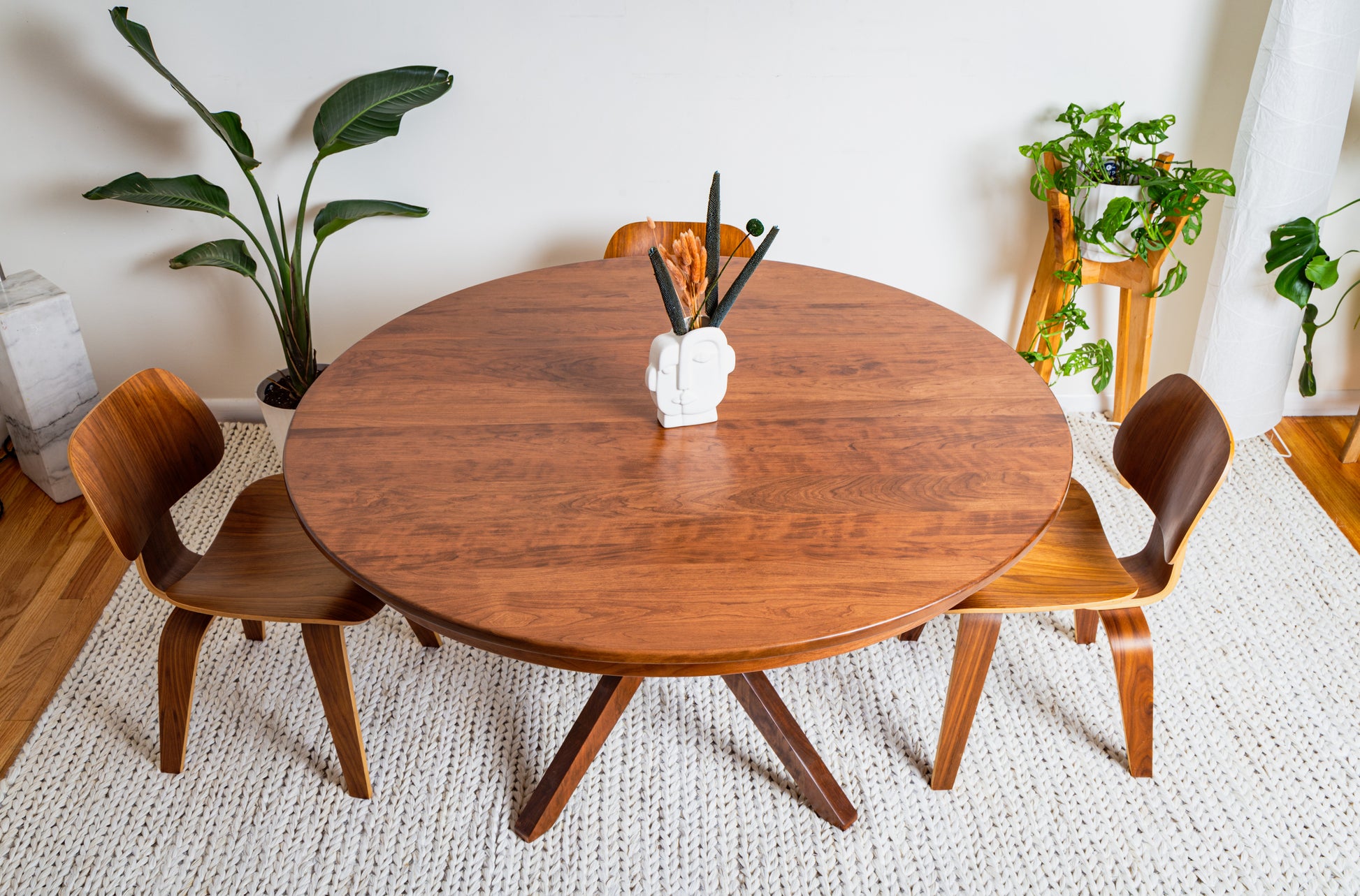 Corcovado: Modern Small Dining Table, extendable for 4 to 8, shown with chairs, vase of pencils, and plants, highlighting its adaptable design.