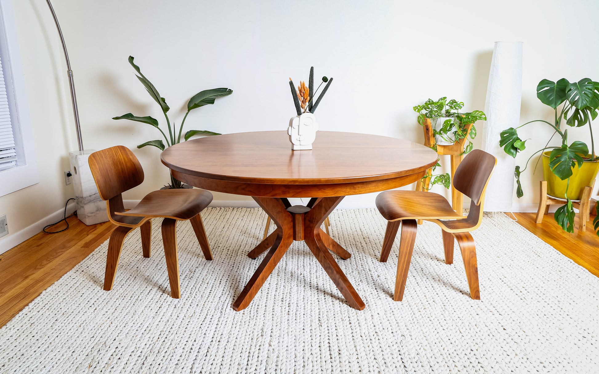 Corcovado: Modern small dining table, extendable for 4 to 8, shown in a room with chairs, a white sculpture, and a potted plant.