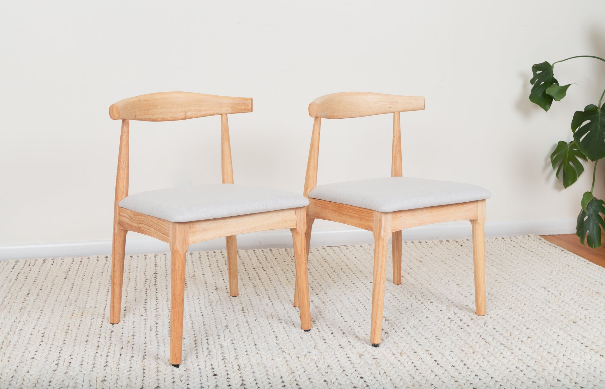 Mid-Century Modern Dining Chair set on a rug, featuring Ox Chair-inspired design with curved backrest and cushion, crafted from durable parawood for ergonomic comfort.