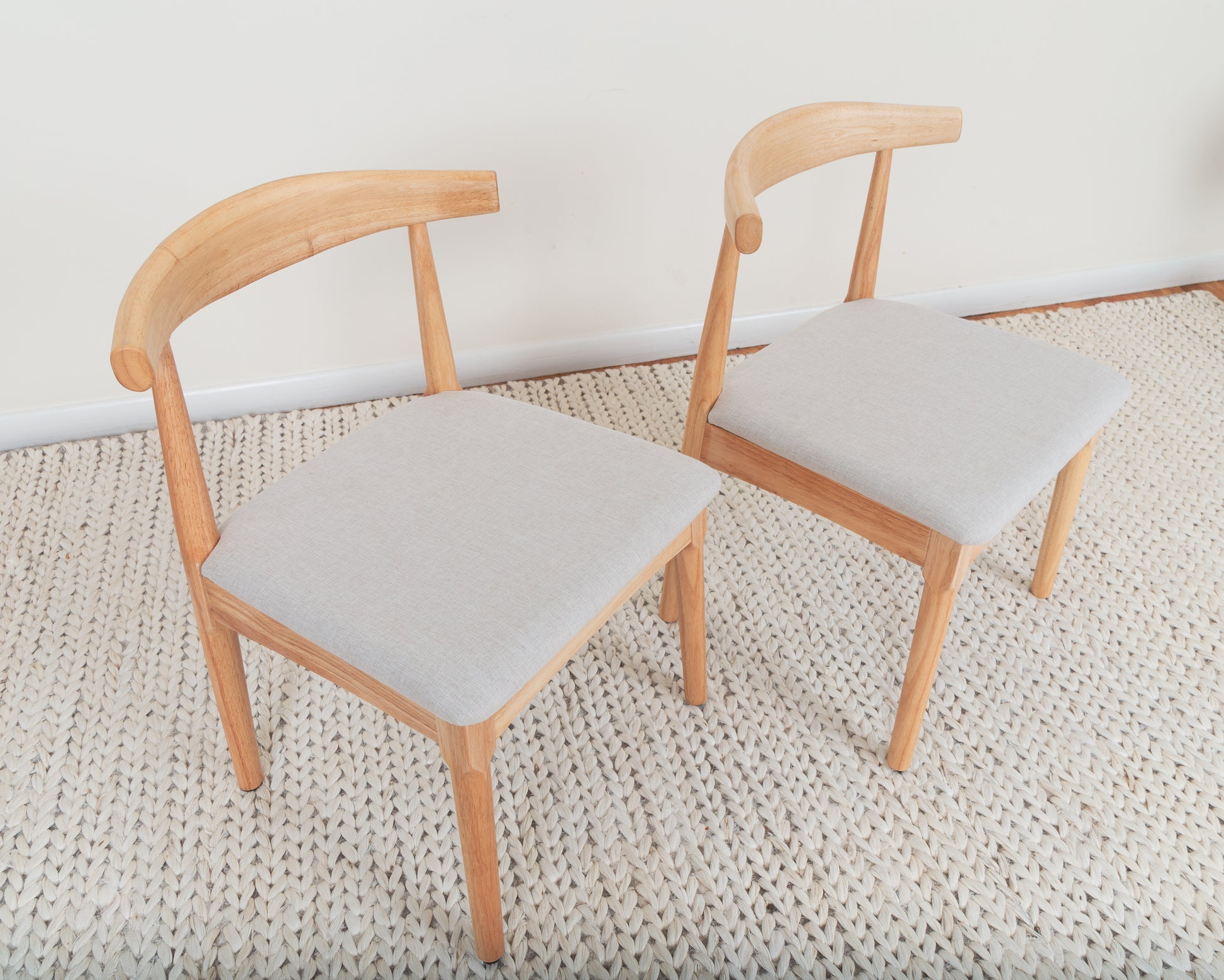 Mid-Century Modern Dining Chair: Pair of parawood chairs with curved backrests and armrests, set on a rug, offering ergonomic comfort and elegance.