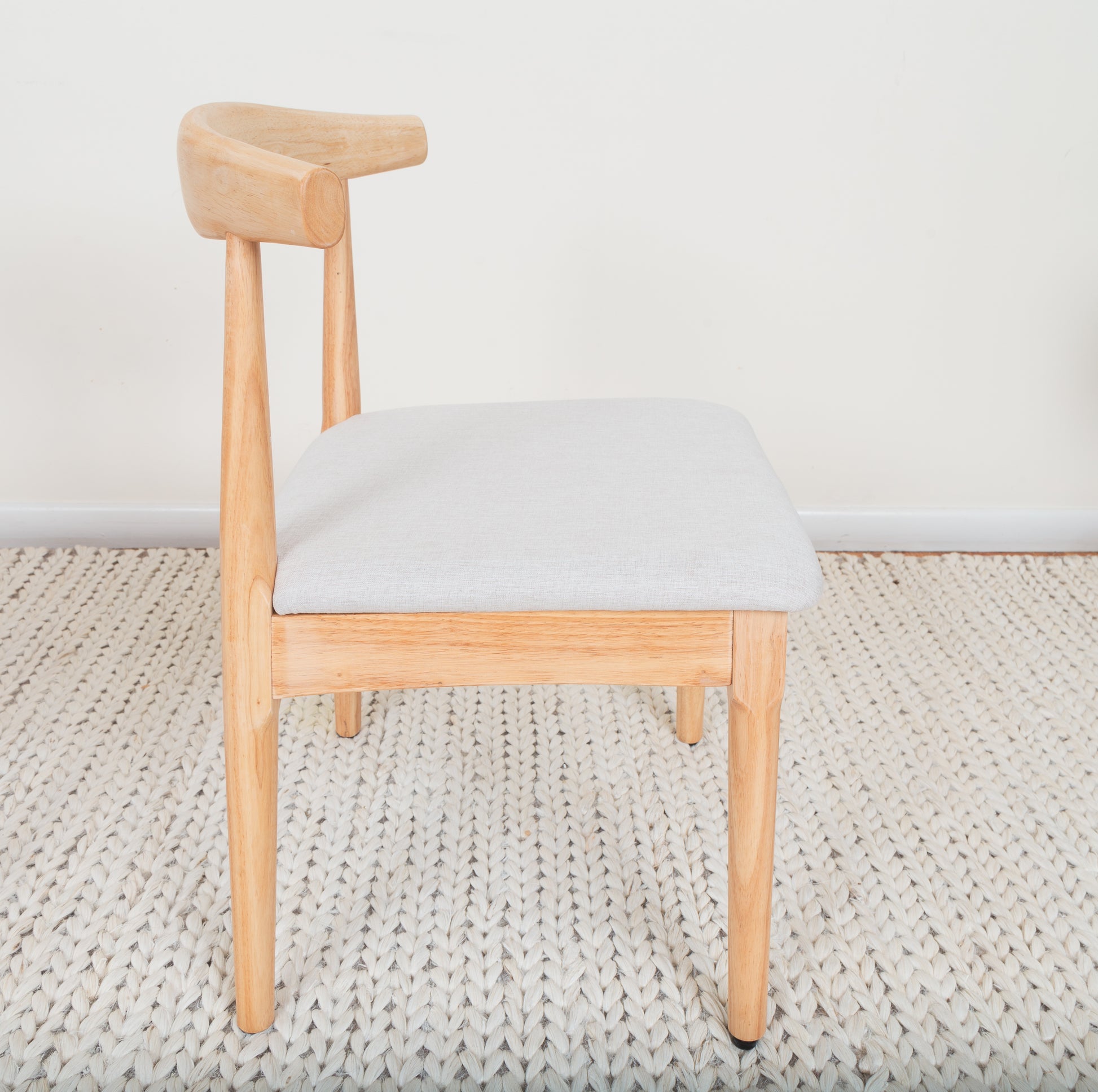 Mid-Century Modern Dining Chair with a curved backrest, wooden frame, and cushioned seat, inspired by Ox Chair design, placed on a rug.