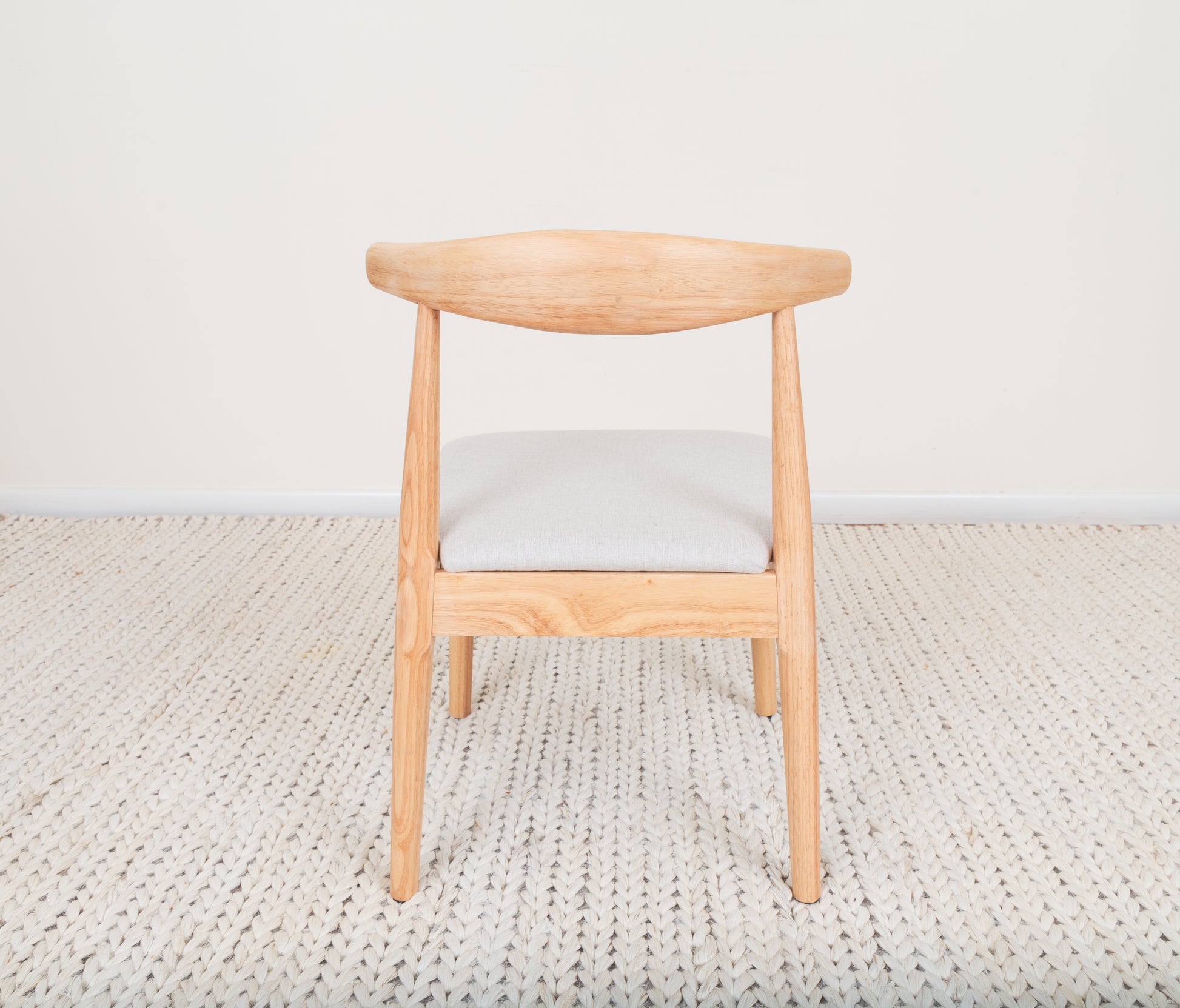 Mid-Century Modern Dining Chair crafted from parawood with a curved backrest and cushion, showcasing Ox Chair-inspired design on a rug.