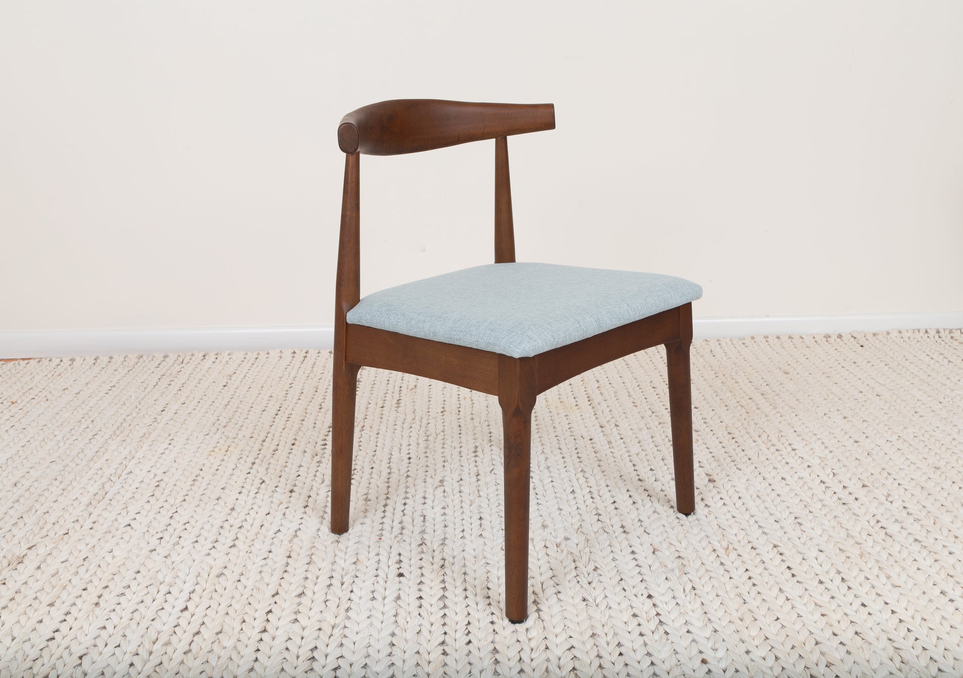 Mid-Century Modern Dining Chair with curved backrest, cushioned seat, and parawood construction on a rug, showcasing ergonomic design and timeless elegance.