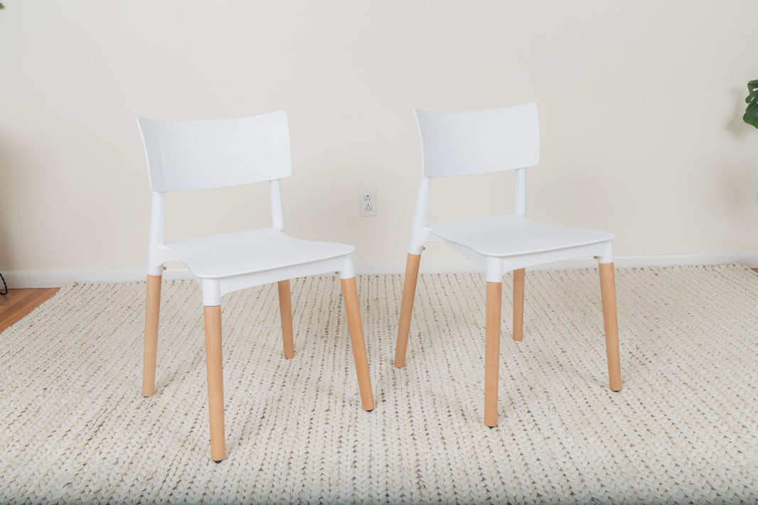 Minimalist White Dining Chair Set featuring a smooth white seat and beech wood legs, showcased in a modern, indoor setting with two chairs on a carpet.