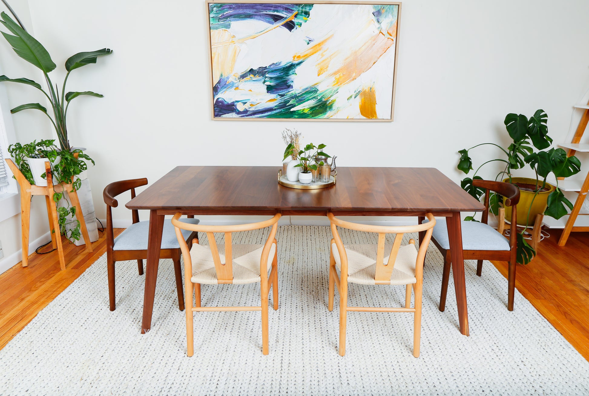 a dining room table with chairs and a painting on the wall