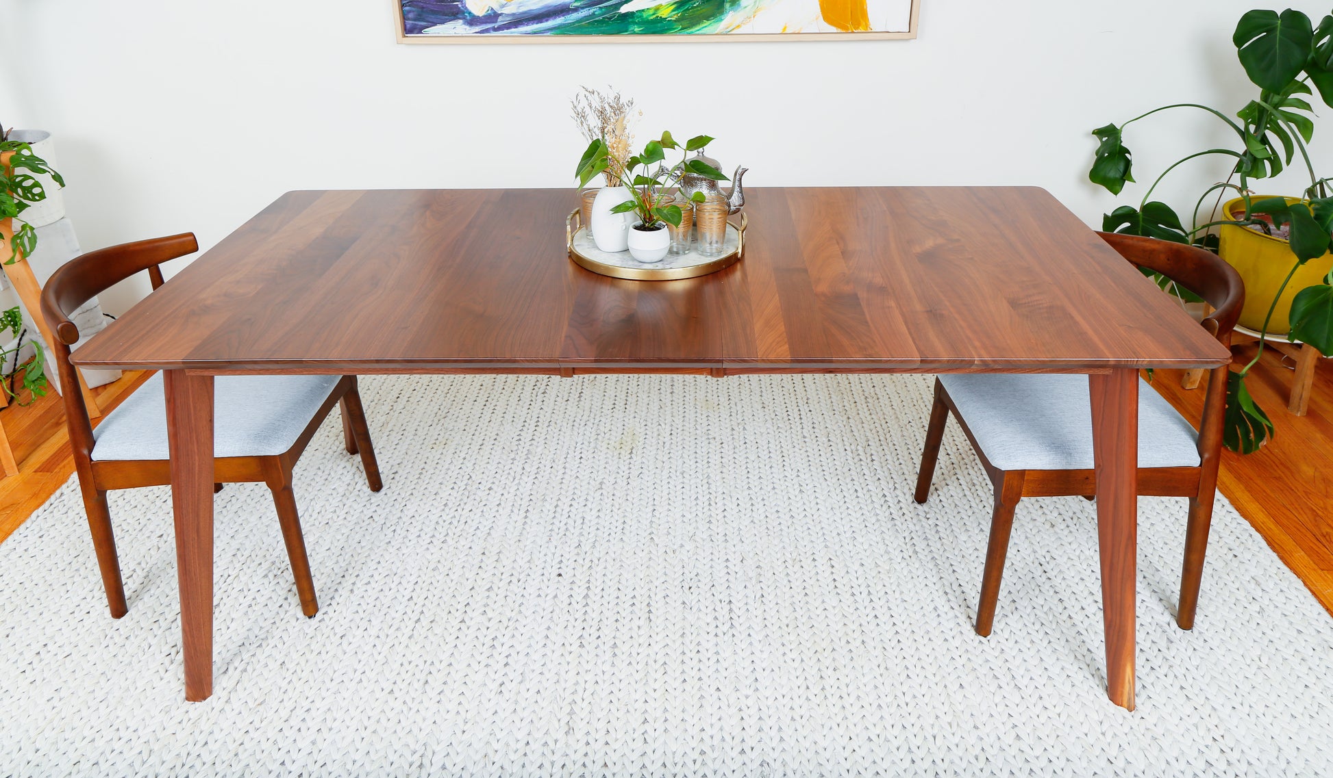 a wooden table with two chairs and a potted plant