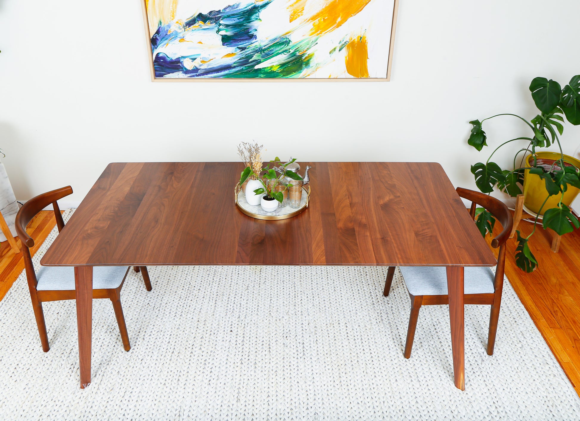 a wooden table with two chairs and a potted plant