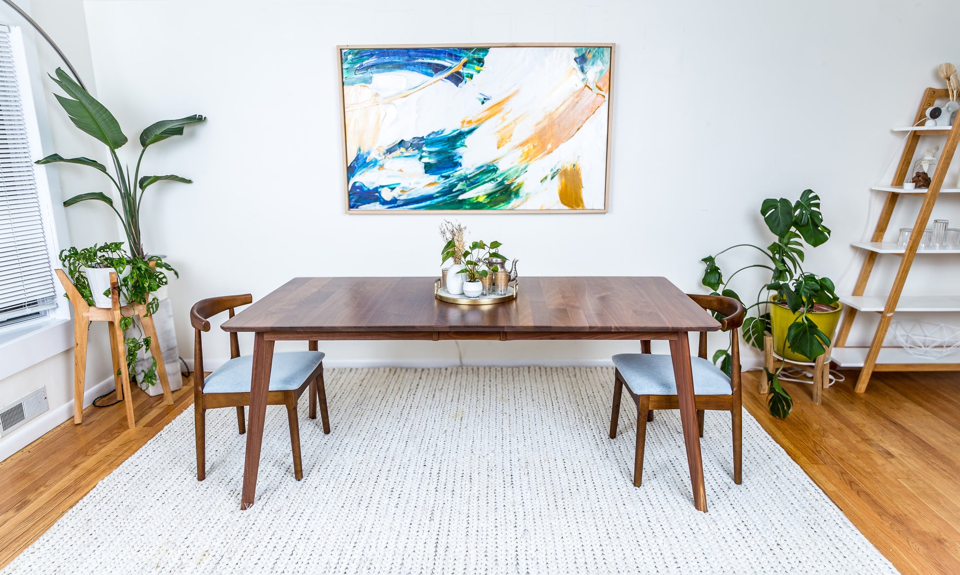 a room with a table, chairs and a painting on the wall