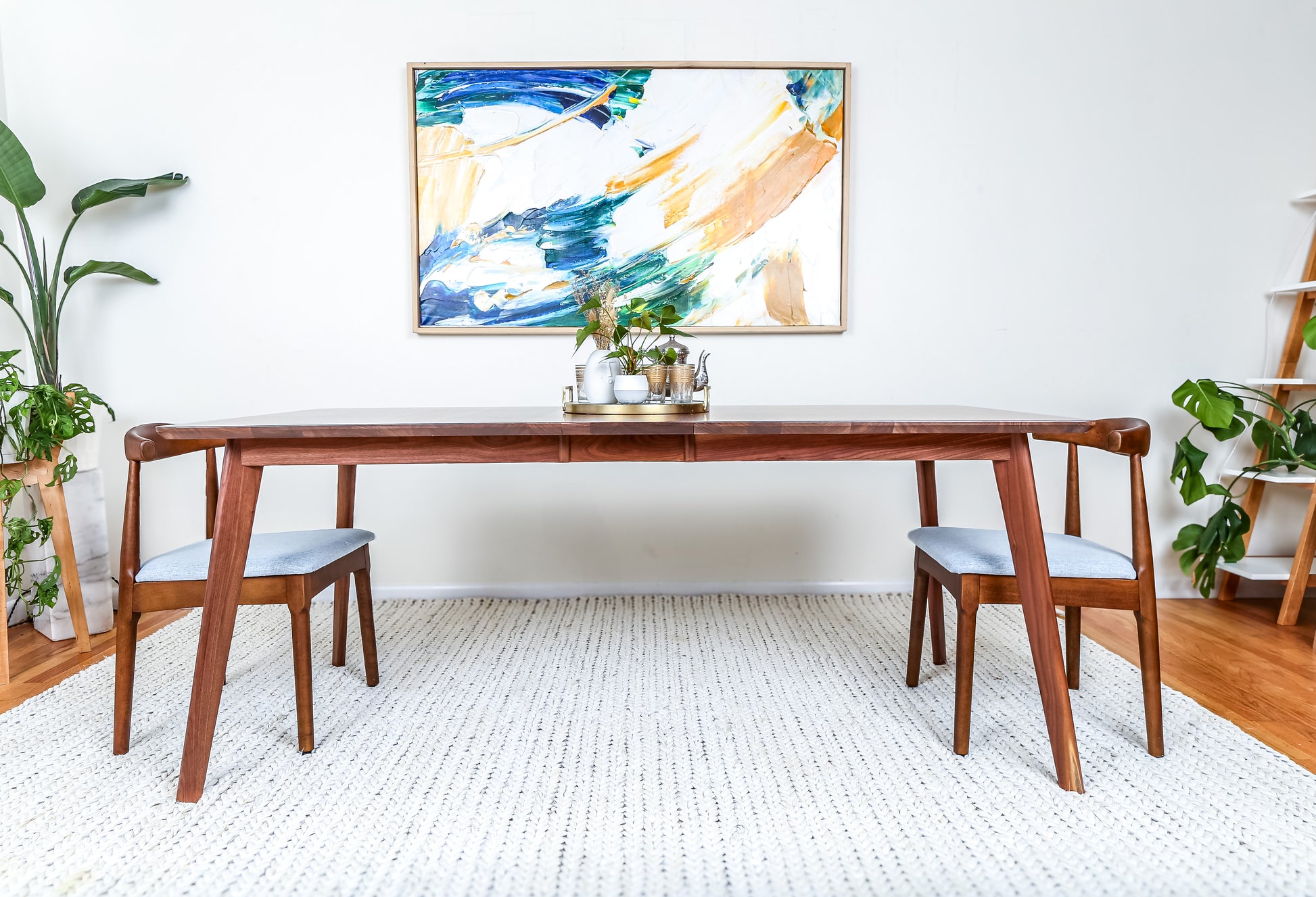 a table with two chairs and a painting on the wall