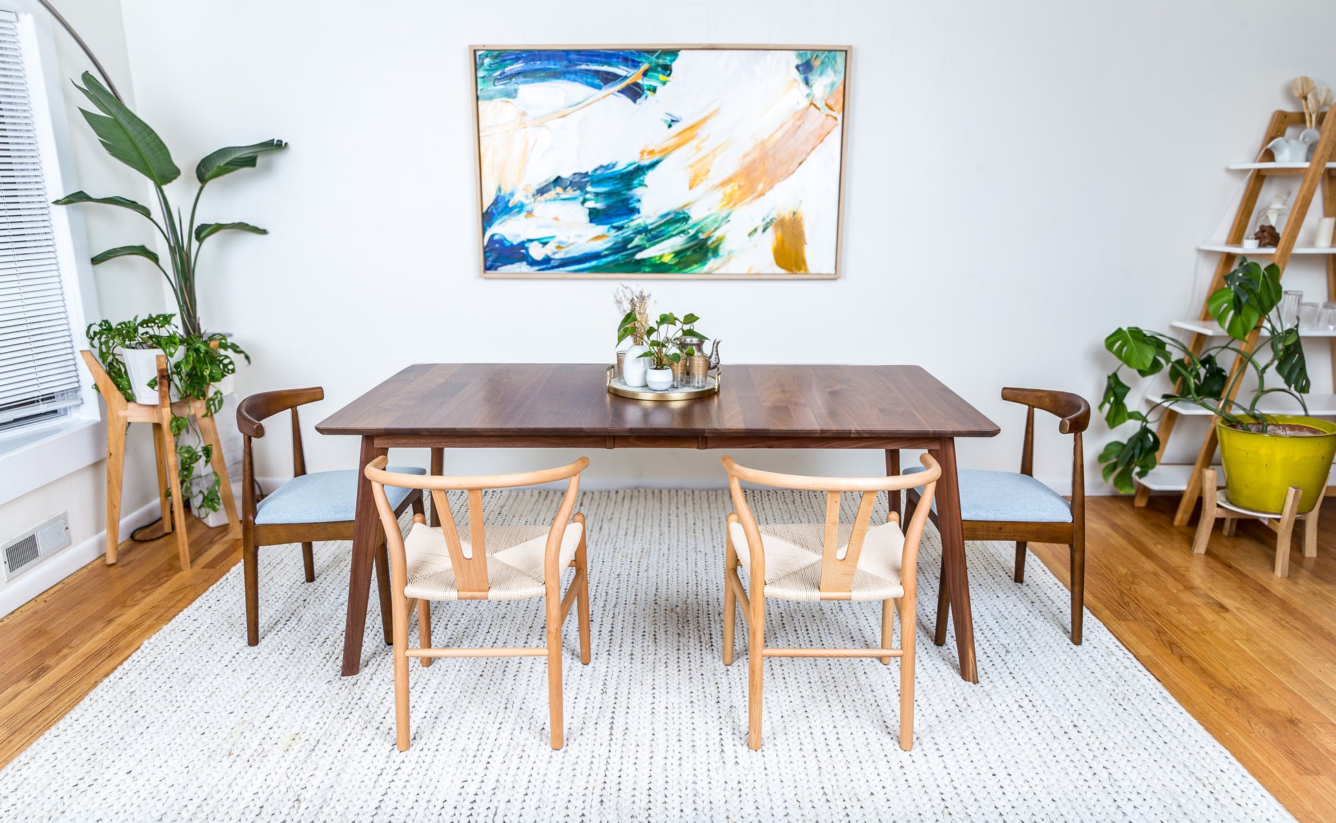 a dining room table with chairs and a painting on the wall