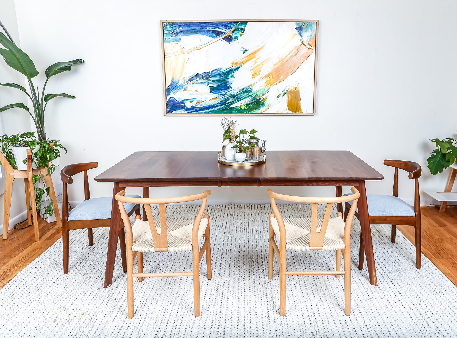 a dining room table with chairs and a painting on the wall