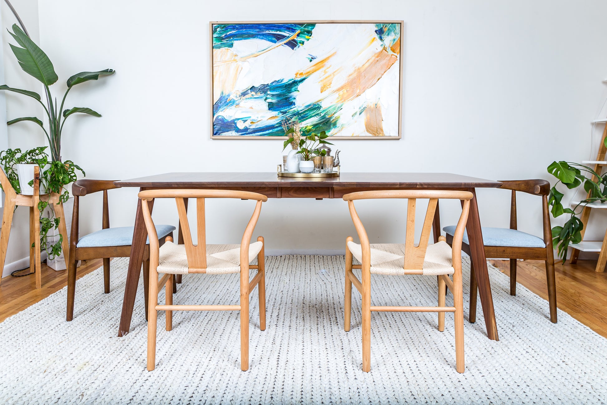 a dining room table with chairs and a painting on the wall