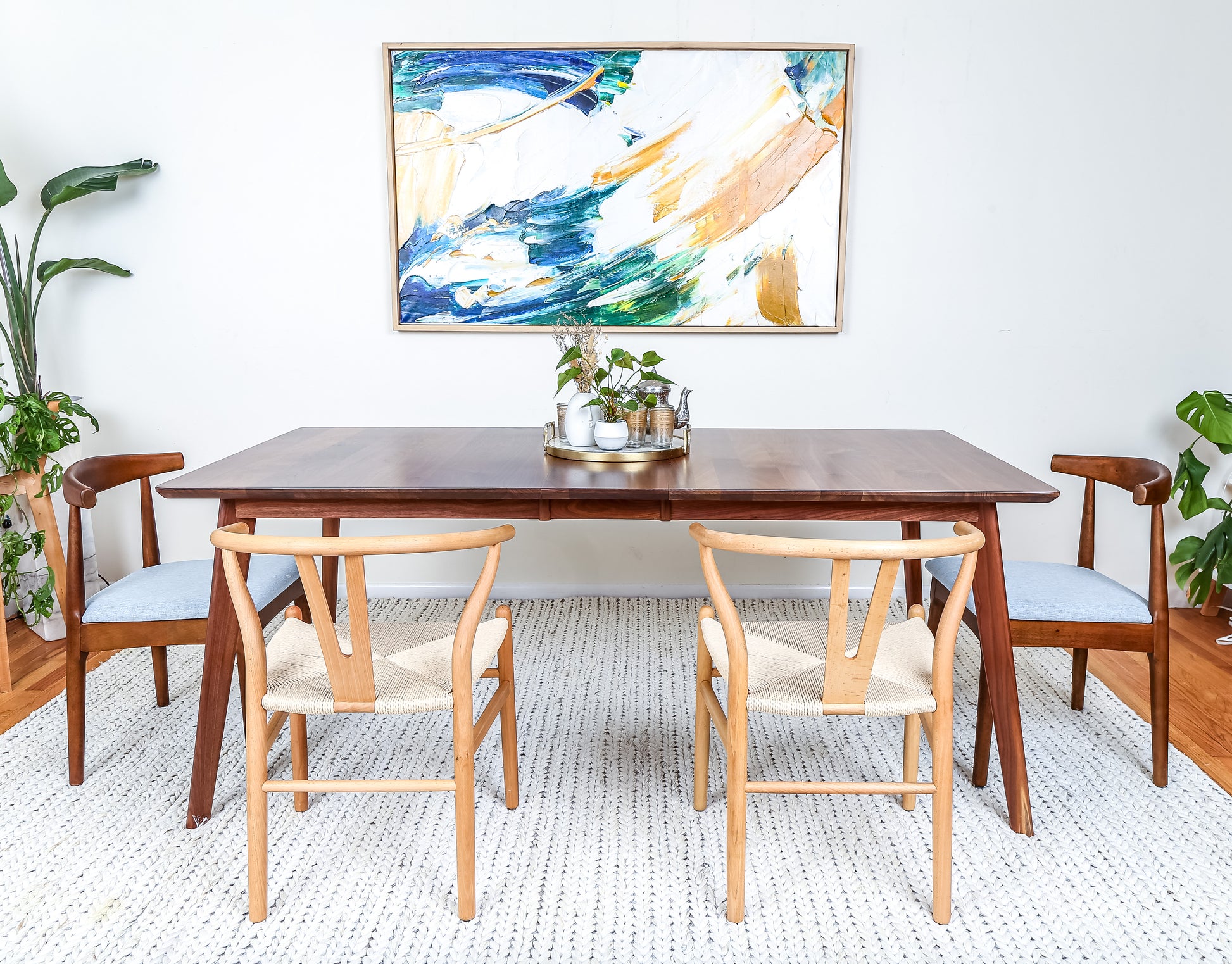 a dining room table with chairs and a painting on the wall