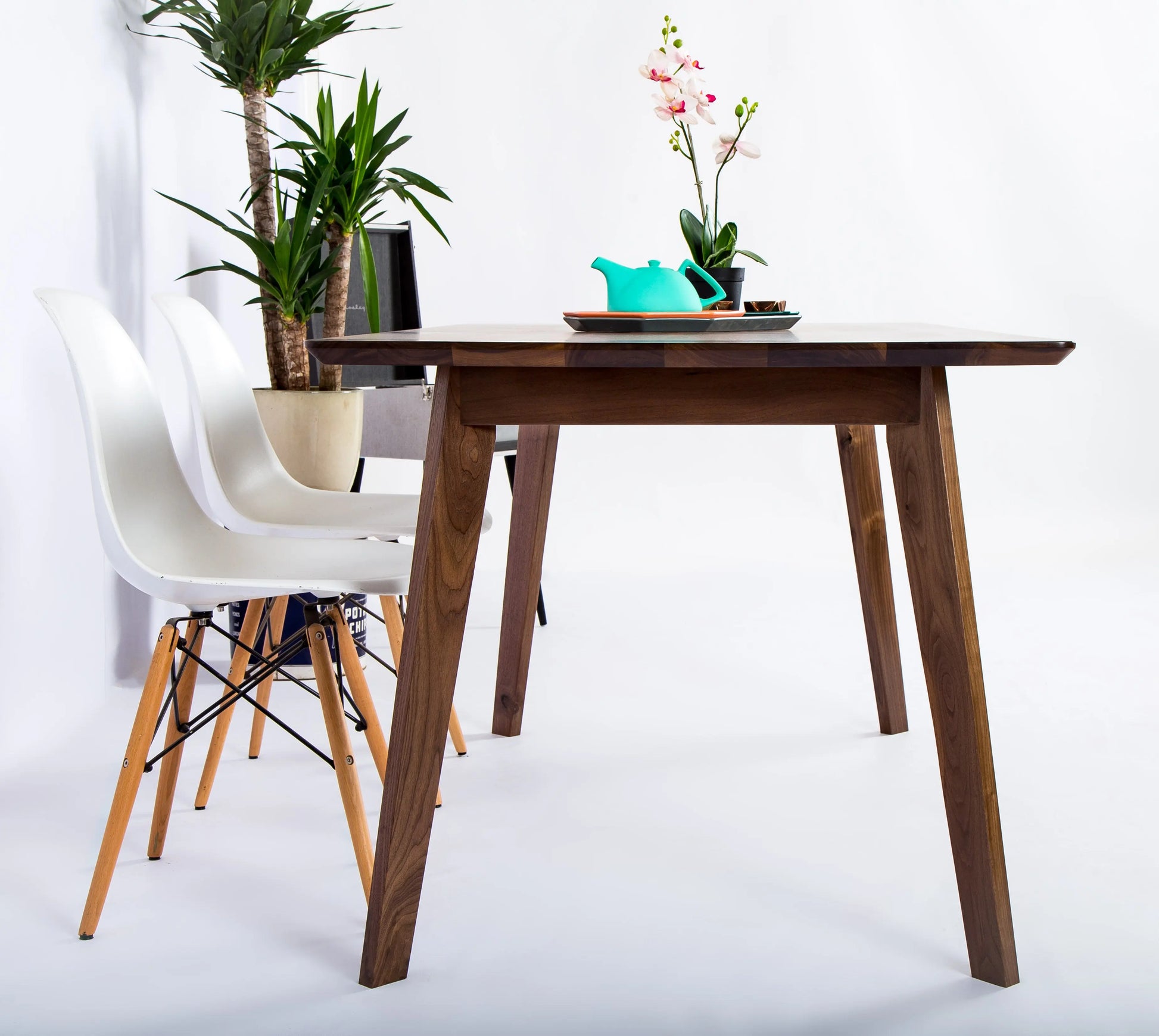 Tapered and angled solid walnut leg system of the small Bossa Nova table
