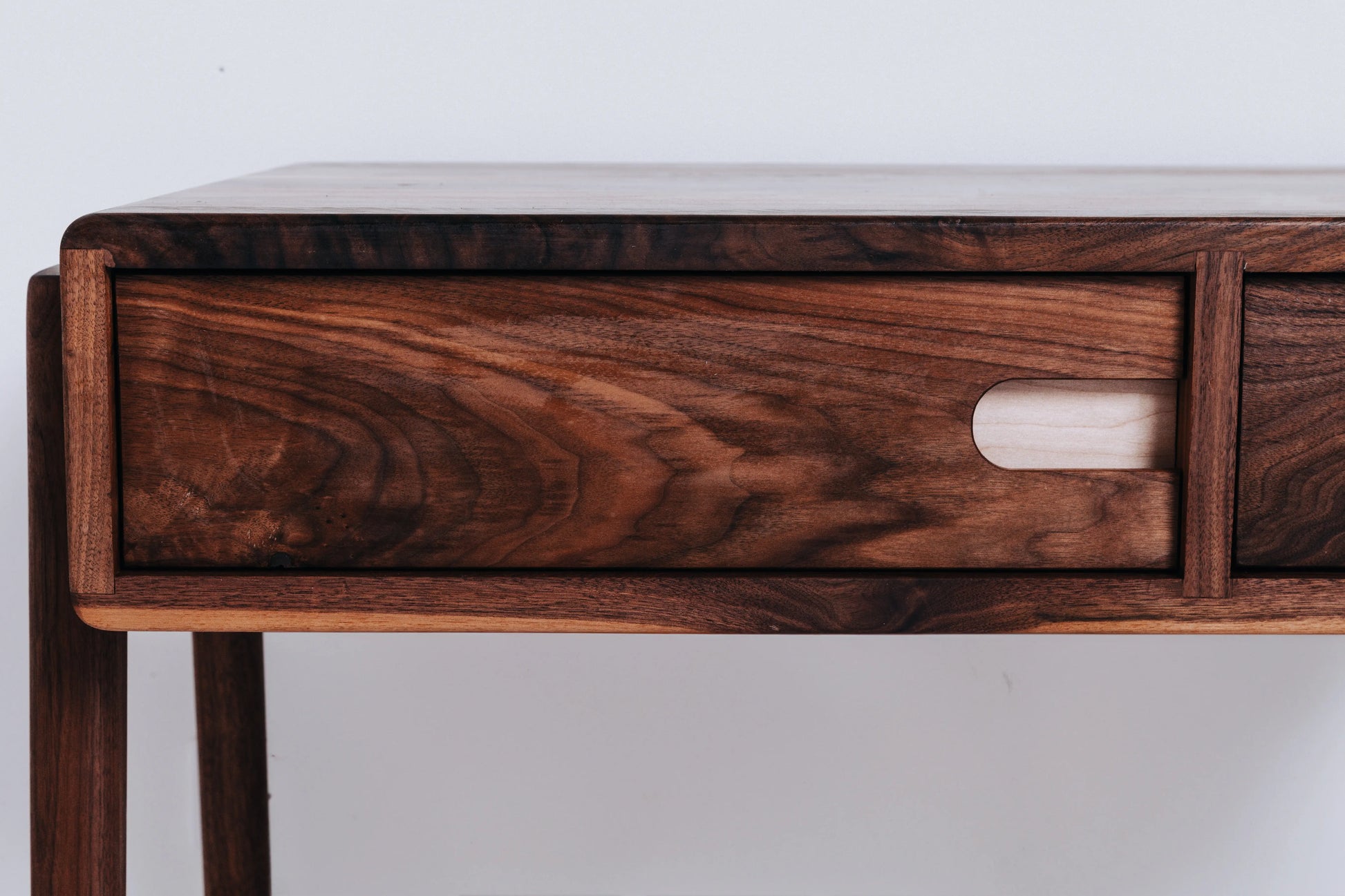 Close-up of Fjord's rock maple pulls on black walnut drawers, showcasing the coffee table's fine craftsmanship
