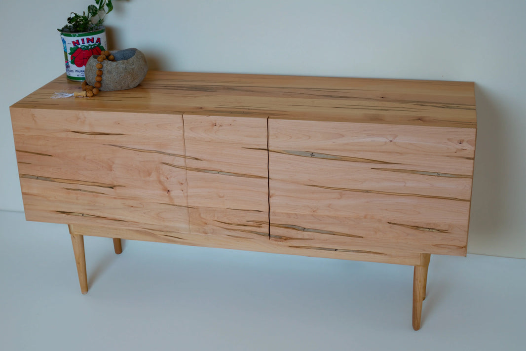 Modern credenza in maple with wavy, bookmatched panels showcasing beautiful grain patterns.