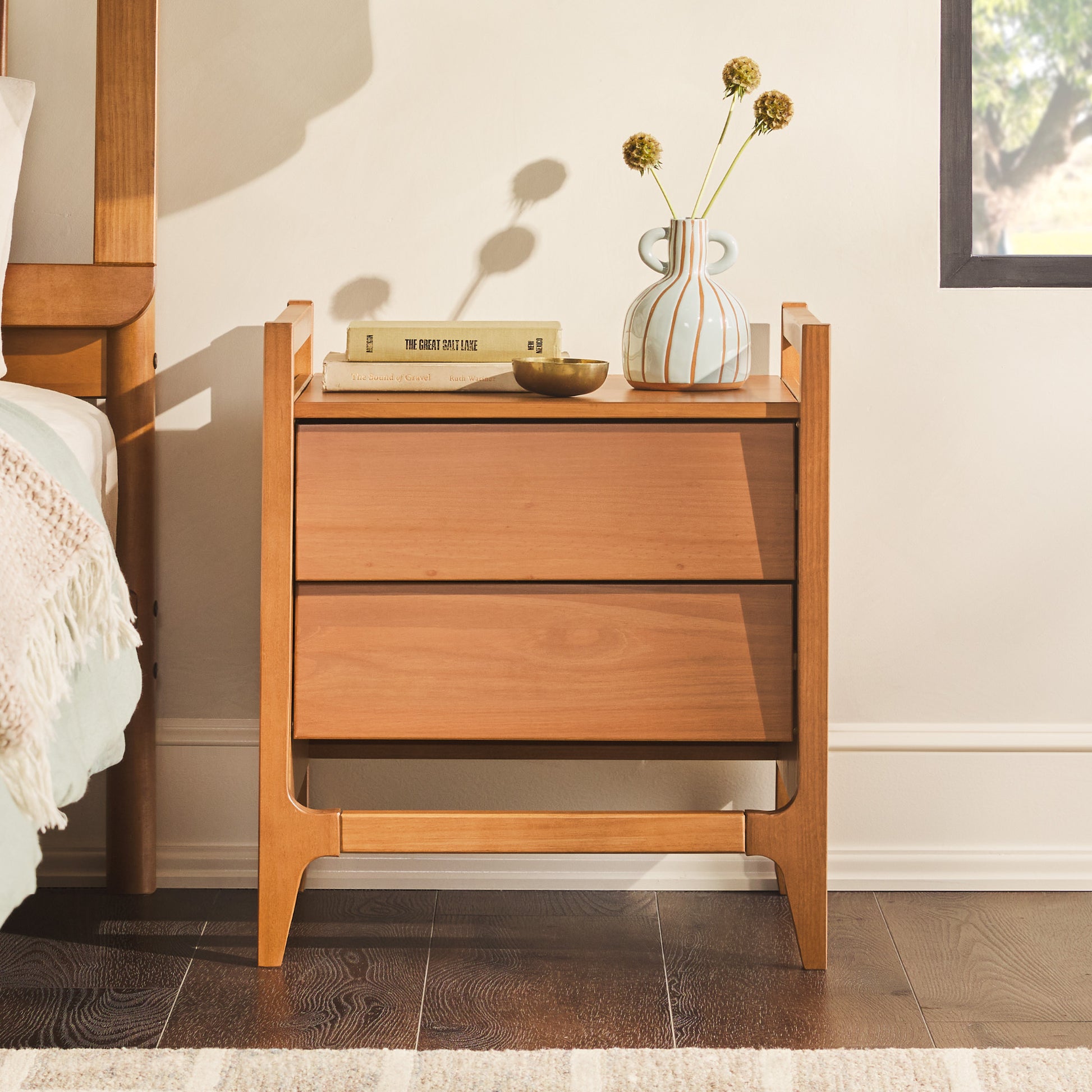 Scandi Angle Face Solid Wood Nightstand – Caramel with angled drawer fronts, topped with a white and orange striped vase, set in a minimalist room.