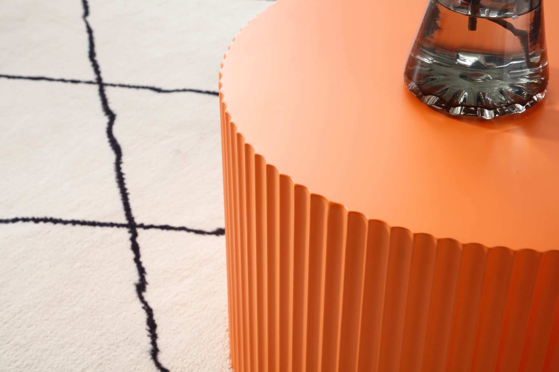 an orange table with a vase on top of it